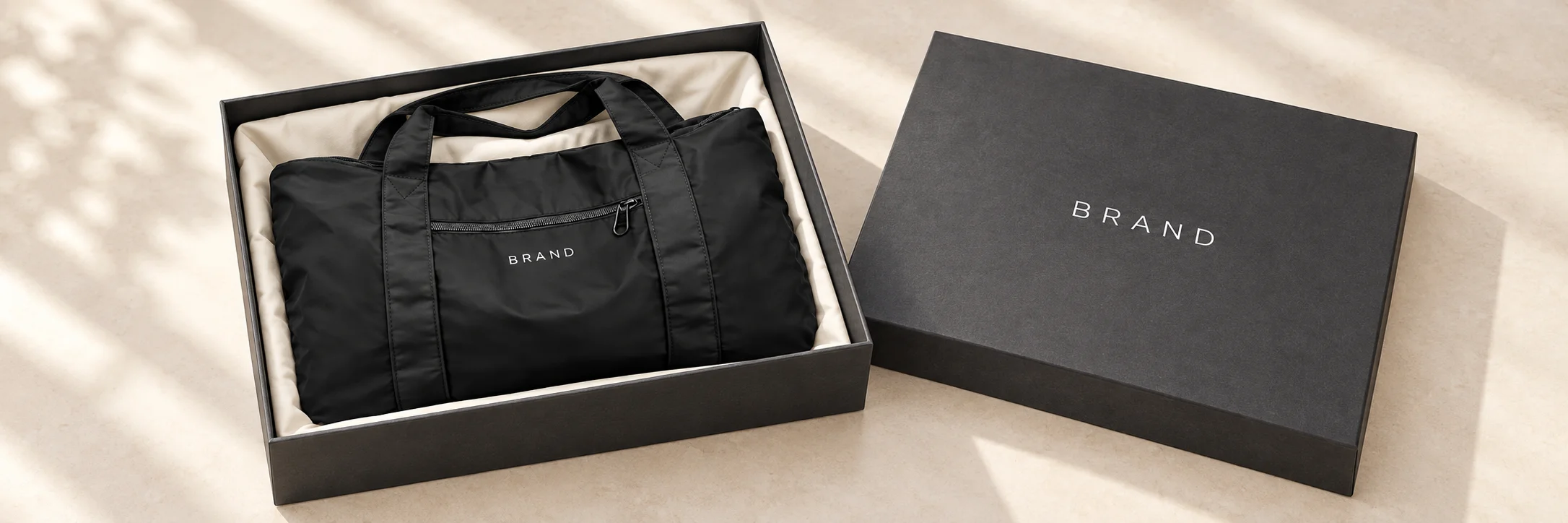 Black nylon duffel beside an open presentation box with tissue paper and a message card.