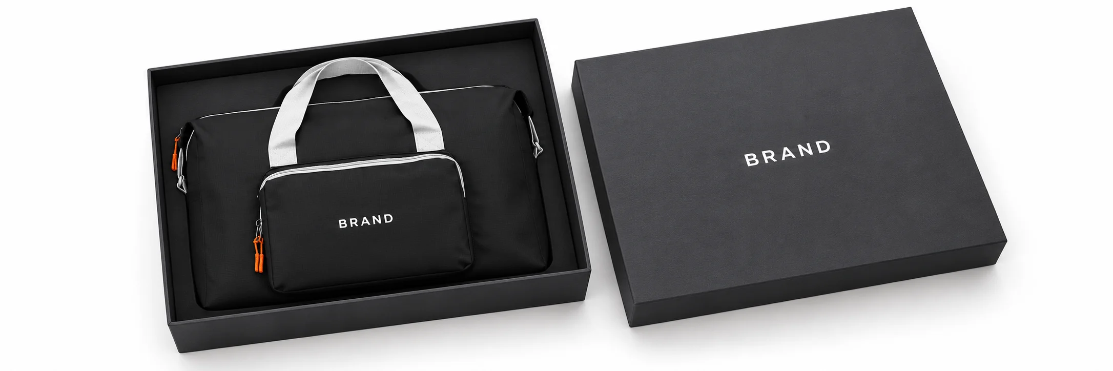 Black weekender with white lettering and light-colored handles arranged inside a charcoal presentation box beside its matching lid.