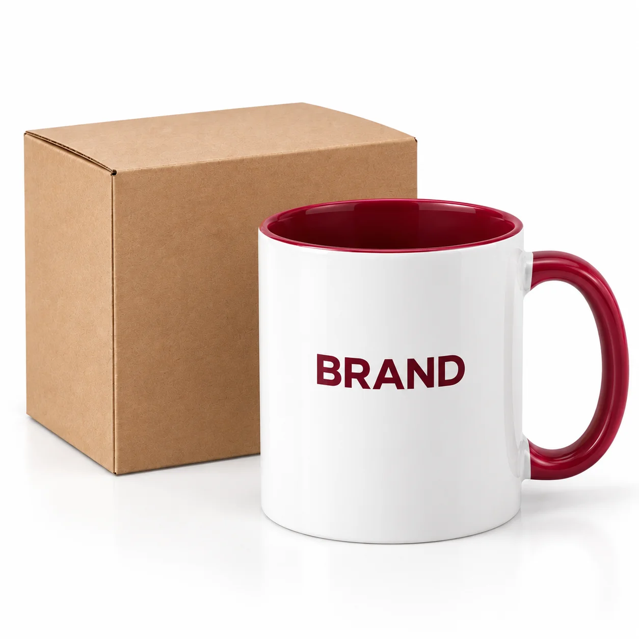 White ceramic mug with burgundy logo printing beside a plain kraft carton.