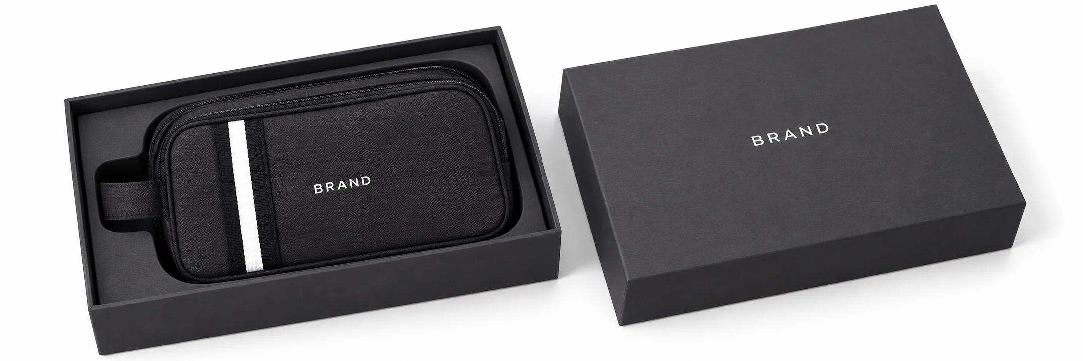 Black striped toiletry bag with white lettering inside a fitted charcoal presentation box beside its matching lid.